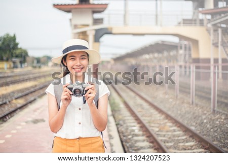 Women tourists carrying a film camera and smiling brightly at the train station