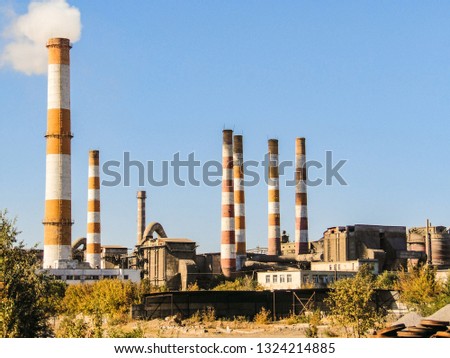 Old factory chimneys on industrial site area. Environmental pollution.