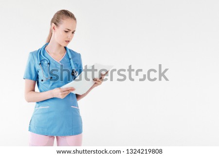 Woman doctor blonde young light gray background studio day beautiful one reads disturbing documents report patient is sick. Operation is difficult taxes credit.