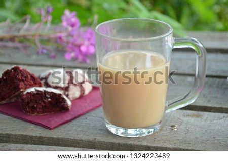 Red velvet cookies next to a cup of coffee. sunny spring or summer morning. pink purple flower