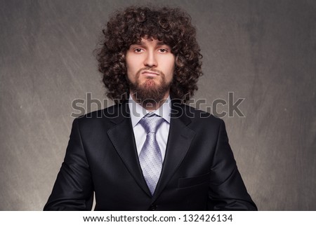 young bored businessman with afro style hair making a facial expression that explains his mood on grunge background