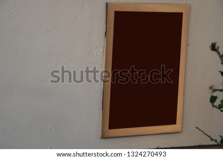 Rectangular sign on white wall. Frame is brass and center is brown