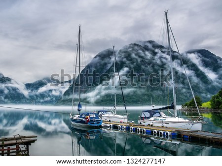 Amazing nature landscape view of lake surrounded by foggy mountains. Sailing vessels or ships. Nature lake. Forest natural. Location: Scandinavian Mountains, Norway. Artistic picture. Beauty world.