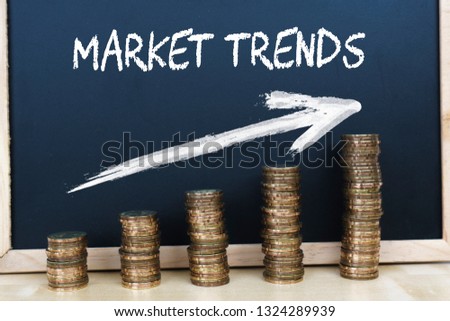 Coins graph with text market trends on the wooden black chalkboard. 