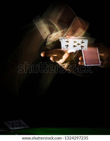 Dealing / Throwing Playing Cards with motion trails on a black background, over a green casino table. Royalty-Free Stock Photo #1324297235