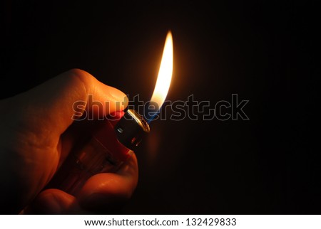 hand igniting lighter in a dark space Royalty-Free Stock Photo #132429833