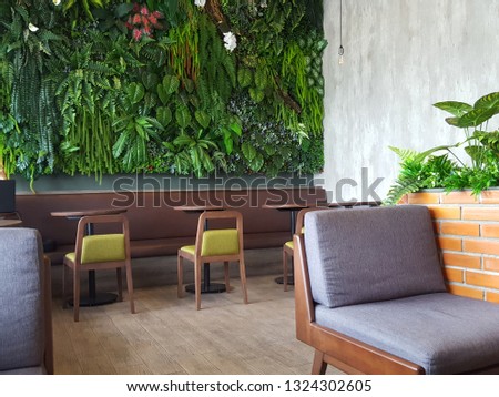 Empty wood table with artificial plant decoration on the wall of ecology design interior. Fake tree from plastic plants ornament design on the wall of coffee shop. Select focus Royalty-Free Stock Photo #1324302605