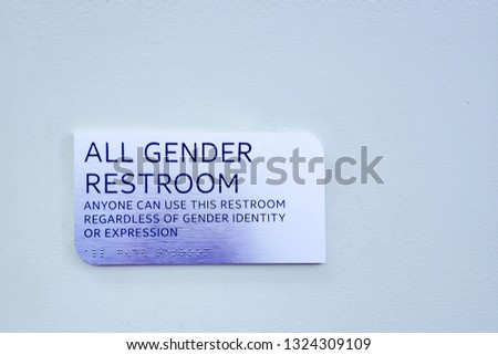 "All Gender Restroom" silver sign on a blue wall