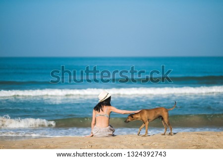 girl looks at the ocean with her dog