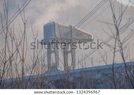 The crane on the power plant dam on Yenisei river in Divnogorsk town. Russian winter near Krasnoyarsk city in Siberia.