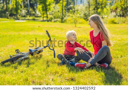 Mom and son rest on the lawn after riding a bike