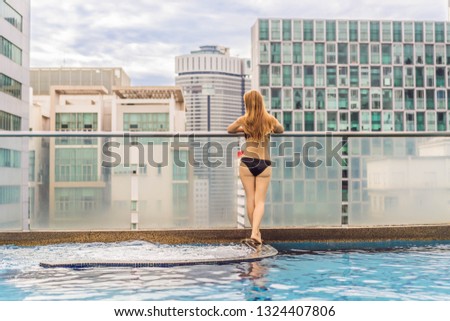Young woman in the pool among the skyscrapers and the big city. Relax in the big city. Rest from stress