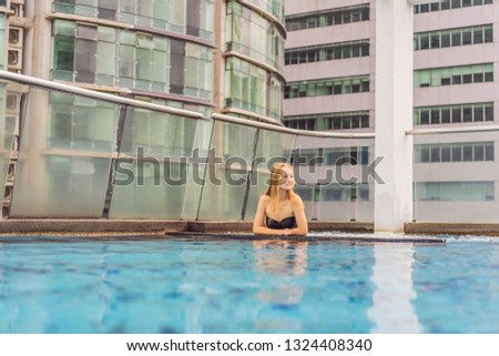 Young woman in the pool among the skyscrapers and the big city. Relax in the big city. Rest from stress