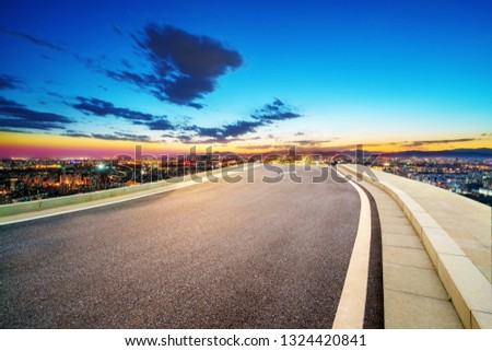 The highway leads to the distant city skyline, Beijing, China.