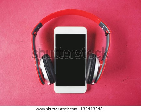 Headphones and smartphone on pink background