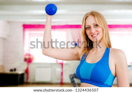 Girl in sports uniform doing exercises in the gym, near sports equipment. Concept of fitness and sports.