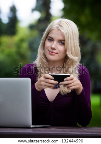 Portrait of beautiful young woman writing status update with smart phone in park