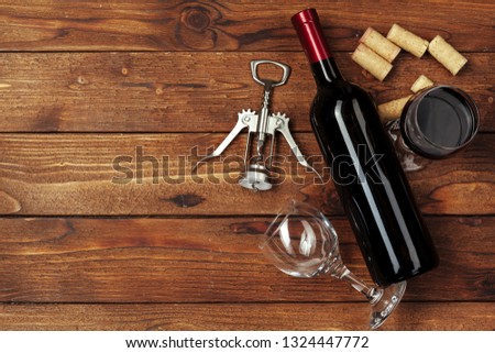 Red wine bottle, wine glass and corkscrew on wooden table background Royalty-Free Stock Photo #1324447772