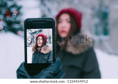 Man hand taking picture of woman in winter with smartphone camera