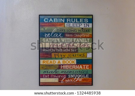 A decorative poster with guest rules on a white cabin wall with many friendly words and suggestions to have a good vacation