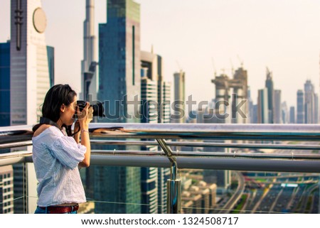 Female tourist taking photo of Dubai downtown cityscape