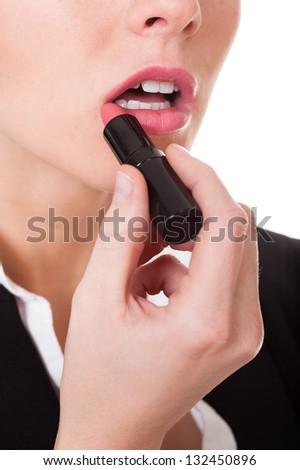 Attractive businesswoman applying lipstick. Isolated on white