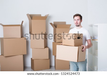 Moving. Young man with carton boxes in new apartment.
