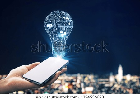 Hand holding smartphone with abstract circuit lamp on blurry illuminated night city background. Engineering and energy concept.