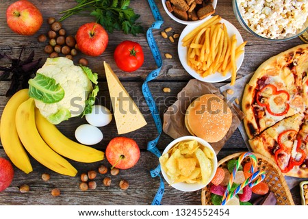 Fastfood and healthy food on old wooden background. Concept choosing correct nutrition or of junk eating. Top view. Royalty-Free Stock Photo #1324552454