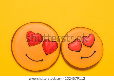 two yellow cookies in the shape of smiles, with eyes in the shape of hearts, on a yellow background, the concept of love