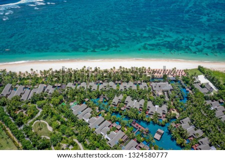 Aerial view of beautiful exotic villas with swimming pools on the white sand beach near the ocean, Nusa Dua, Bali, Indonesia