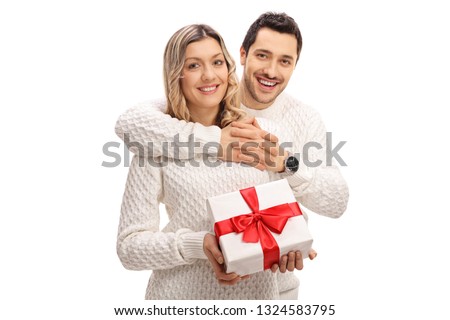 Young man hugging a young woman holding a wrapped gift box isolated on white background
