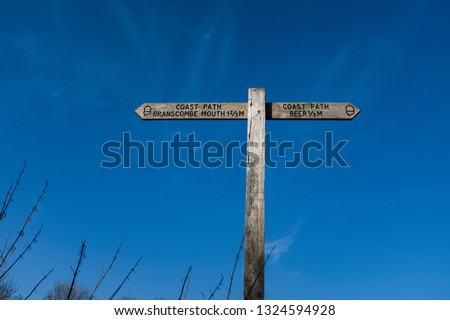 A wooden sign showing the coastal path along a stretch of Devon coastline
