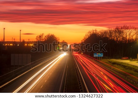  the light trails on motorway highway during a dramatic sunset