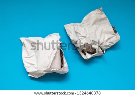 Damaged polyethylene envelope on blue background. Plastic Postal Mailing Bags