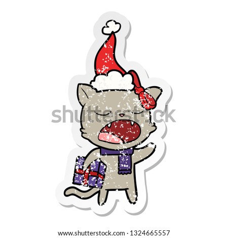 hand drawn distressed sticker cartoon of a cat with christmas present wearing santa hat