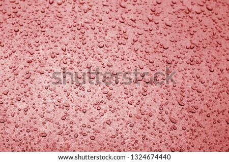 Water drops on car surface in red tone. Abstract background and texture for design.