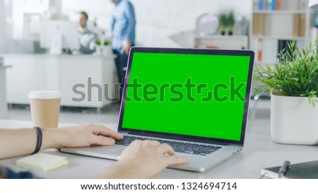 Close-up of a Man's Hands Working on Green Screen on a Laptop. In Background Blurred and Brightly Lit Office where One Man Approaches the Other and They Have Discussion.