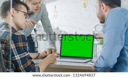 Three Creative Men Discuss Business around Green Screened Laptop. They're in Bright Modern Office.