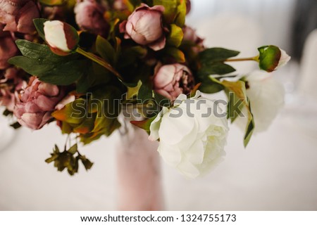 Flower bouquet of artificial peony flowers on a table.