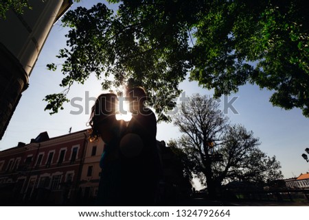 A close-up of a guy and a girl embracing each other on the square of the city. the sun shines for a couple