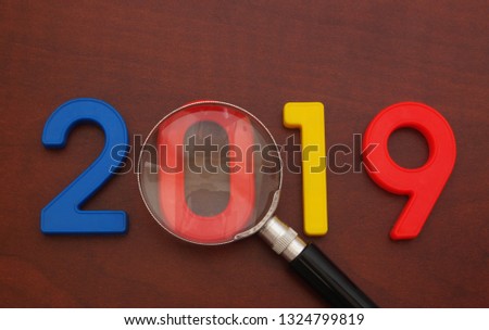 Main events in year 2019 concept. Magnifying glass and numbers 2019 on wooden table.