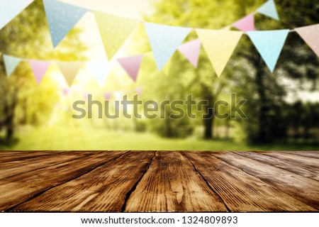 Desk of free space for your decoration in sunny spring garden. Green trees of leaves and easter decoration of garlands. 