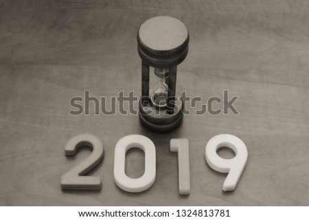 Hourglass and numbers 2019 on wooden background