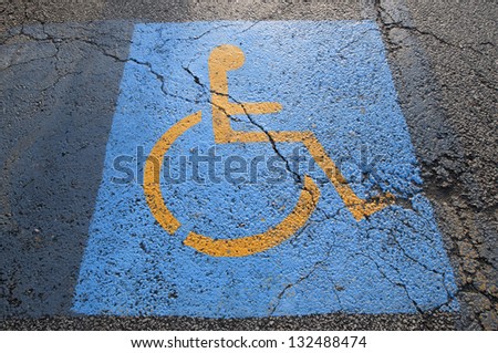 Cracks in parking lot pavement on handicapped parking spot  signifying failing infrastructure