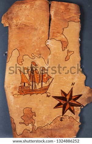 Sea map with illustrations of sailing vessel and compass rose on the order of antiquities on natural wooden background from birch bark 