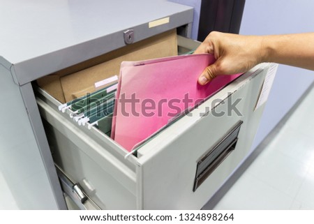 Close up Hand of Man Search files document in a file cabinet in work office, concept business office life.