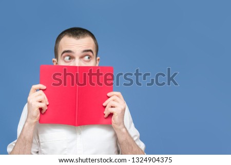 Guy is shocked after reading the book, surprised, avert their eyes, blue background, copy space, for advertising, slogan, front view, blue background