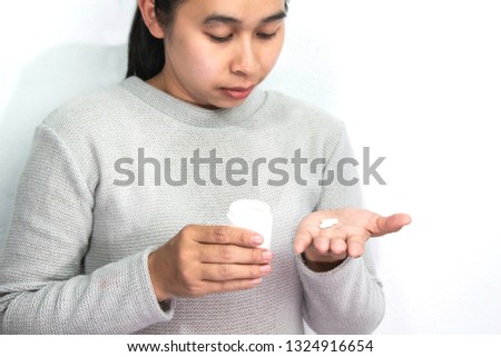 Asian woman standing over white background holding medicine pills, Healthcare concept.