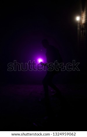 Super hero silhouette holding fireball. Mystery fighter. Dark room. Velvet light. Vertical orientation 